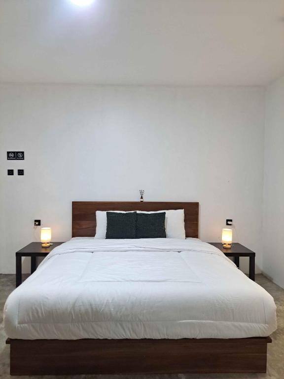 a bedroom with a large bed with two lamps on tables at Second Point View BK in Batukaras