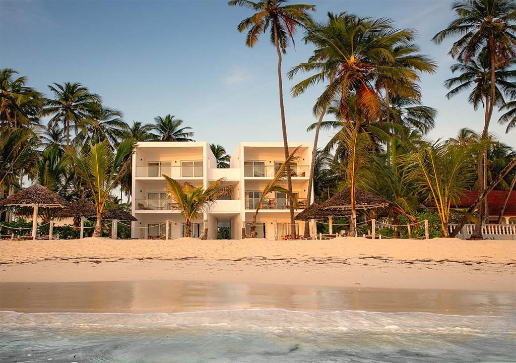 a building on a beach with palm trees and the water at Private Beach Front 2-Bedroom Apartment, Groundfloor in Kiwengwa