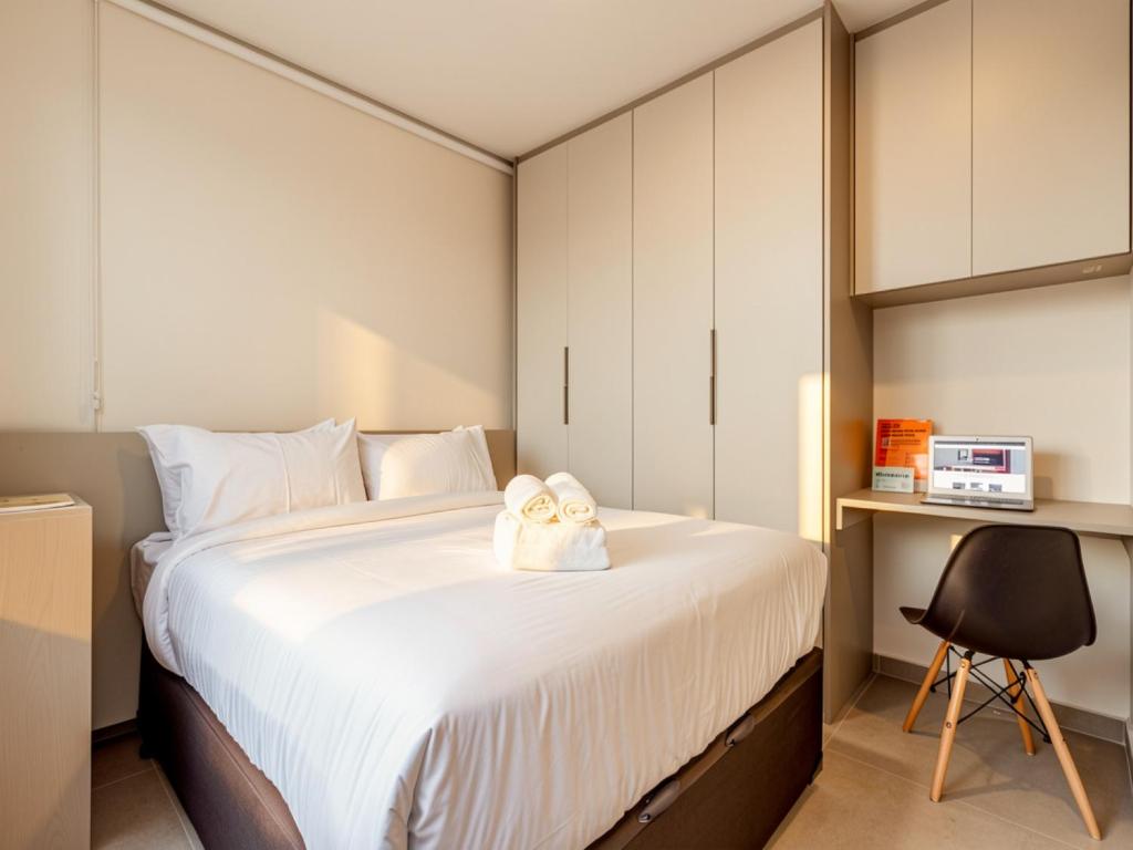 a bedroom with a large white bed with two towels at Xtay Vila Madalena - Stay close to everything with an outdoor pool and access to the best coworking spaces in Vila Madalena in São Paulo