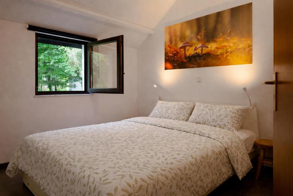 ein Schlafzimmer mit einem Bett und einem Gemälde an der Wand in der Unterkunft Maison 25 in Houffalize