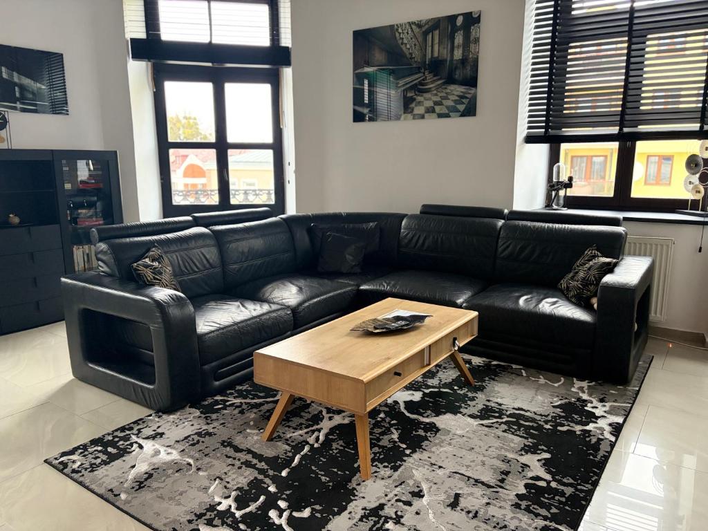 a living room with a black leather couch and a coffee table at Apartamenty Łuczkowskiego z widokiem na Stary Rynek i Studnie 1 102m2 in Chełm
