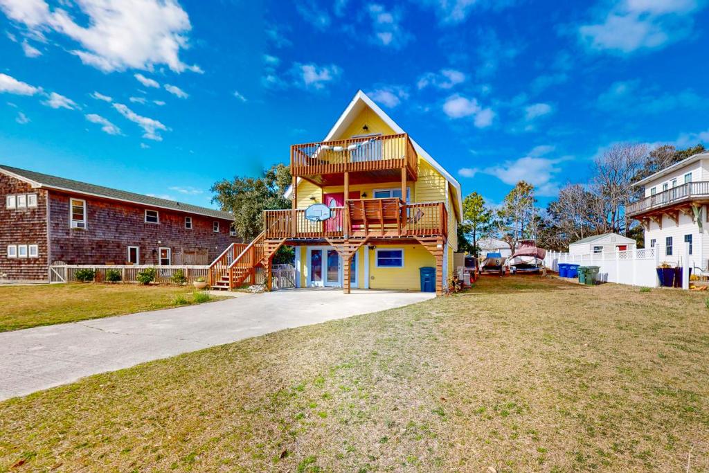 a yellow house with a deck and stairs on it at Sunshine Days OBX in Nags Head