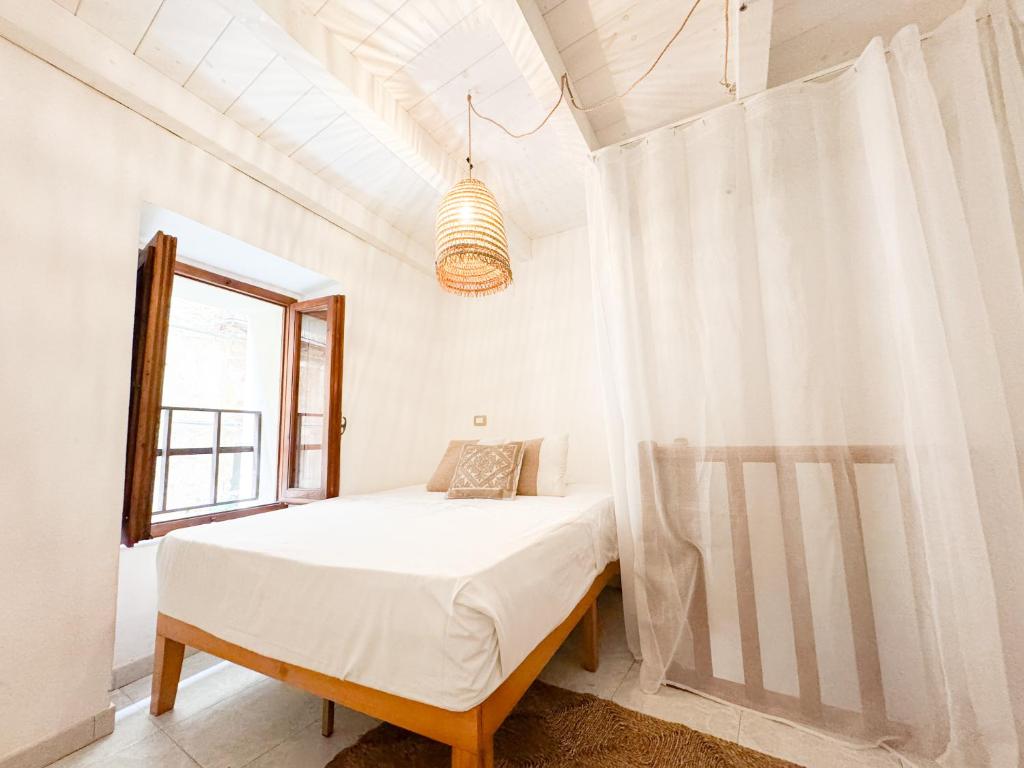 a white bedroom with a bed and a window at Kalma - at the picturesque Via Stretta in Cagliari