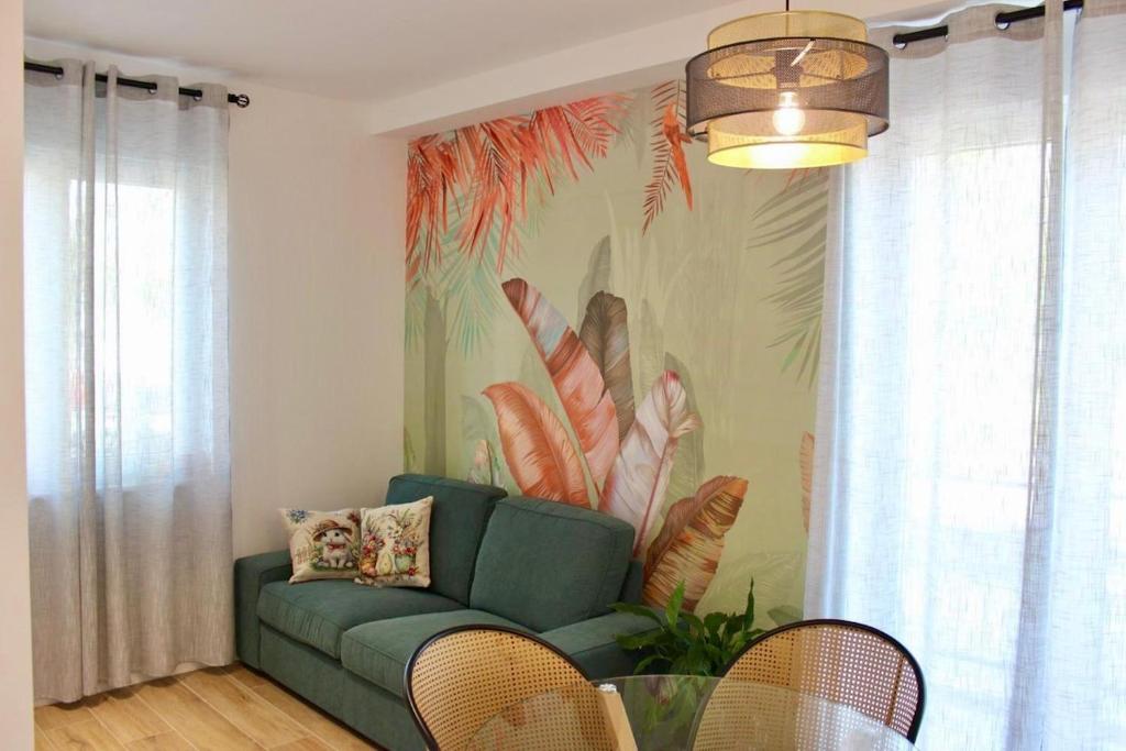 a living room with a green couch and a tropical mural at MB House in Sistiana