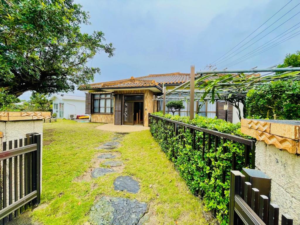 a house with a fence in front of a yard at 与那国島一棟貸切宿はいぬきち in Yonaguni