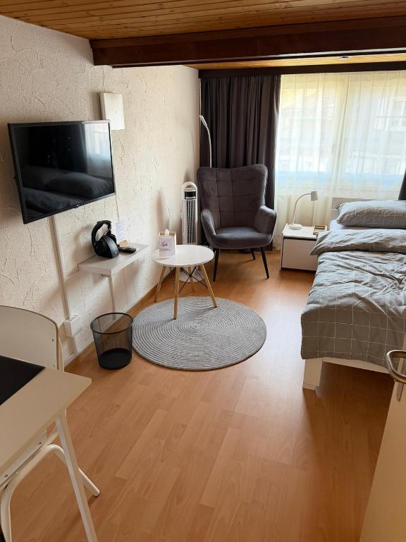 a bedroom with a bed and a chair and a tv at Gästehaus Eichberg, Rheintal in Eichberg