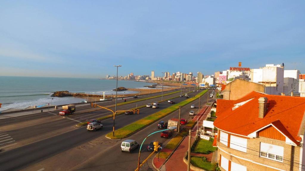 una concurrida calle de la ciudad con coches en una carretera junto al océano en Departamentos Capurro en Mar del Plata