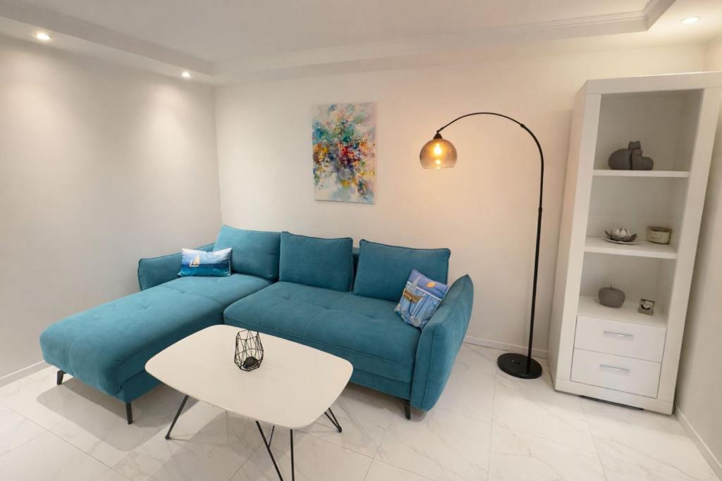 a living room with a blue couch and a table at Apartman Lucija in Selce