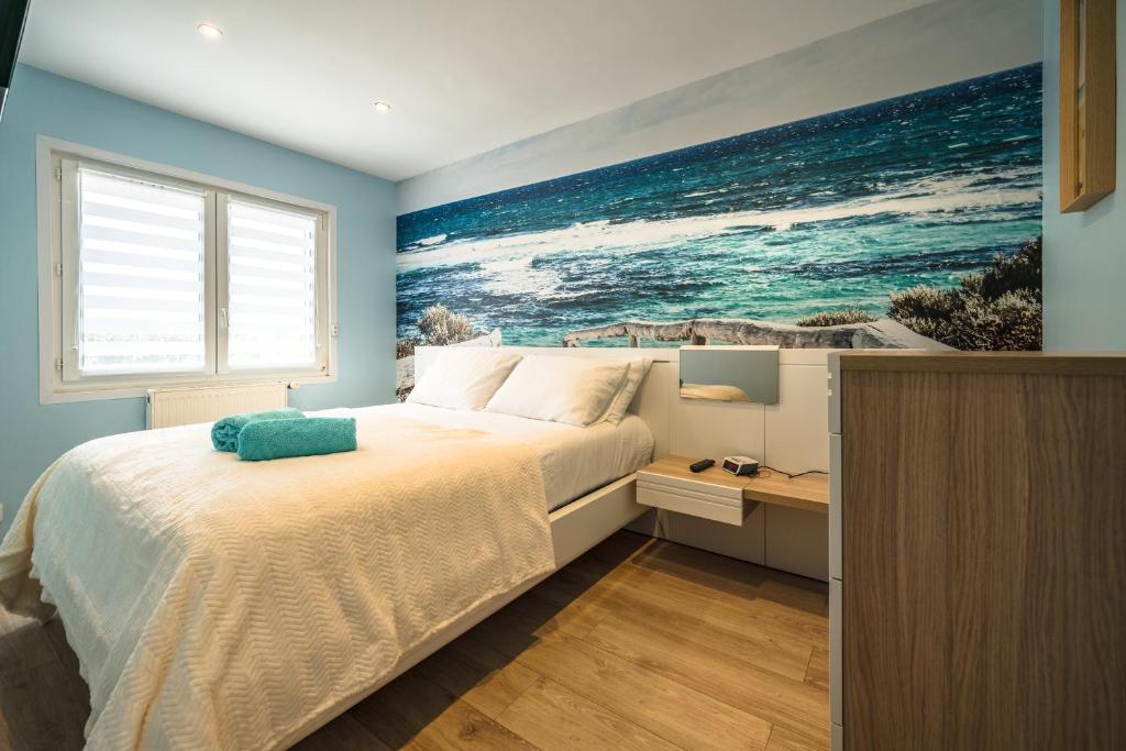 a bedroom with a bed with a painting on the wall at Cocon des dunes in Camiers