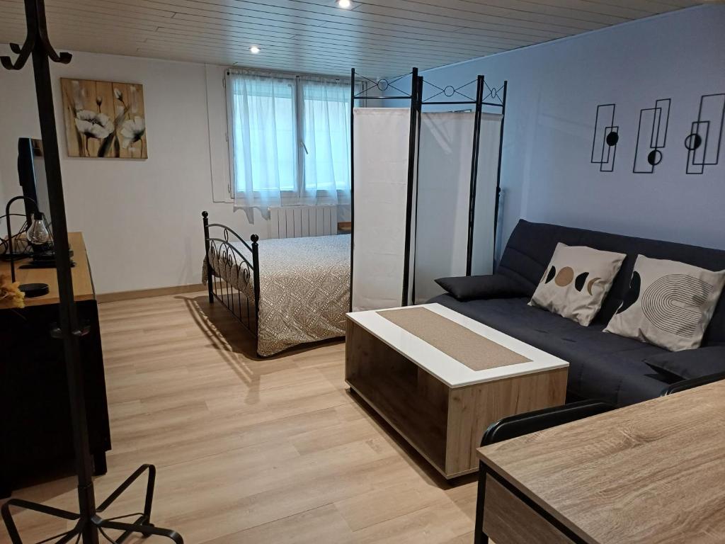 a living room with a blue couch and a bed at Charmant studio au rez de chaussée in Arbois