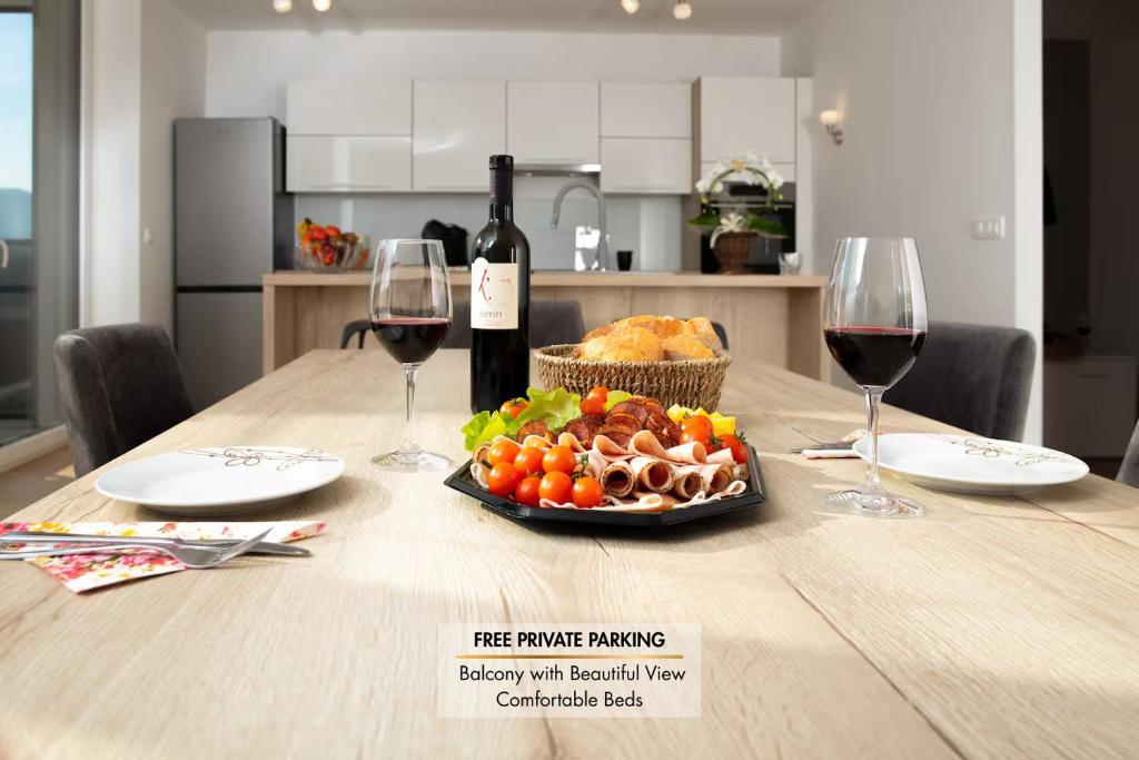 a table with a plate of food and two glasses of wine at DALGONA apartma Godler, Podčetrtek in Podčetrtek