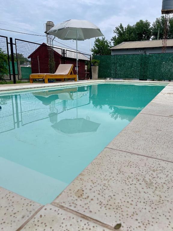 a swimming pool with blue water and an umbrella at Complejo Juan Pablo in Colón
