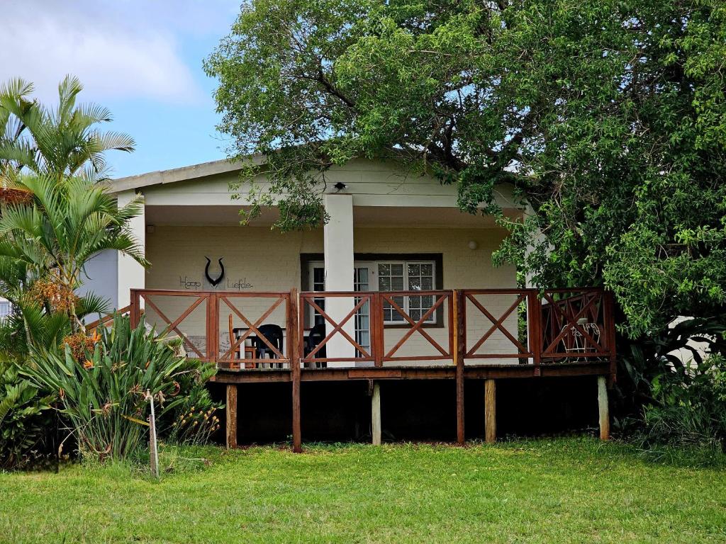 a house with a deck with a dog sitting on it at Schuilhoek Farm House at Ngweni Private Game Farm in Hluhluwe