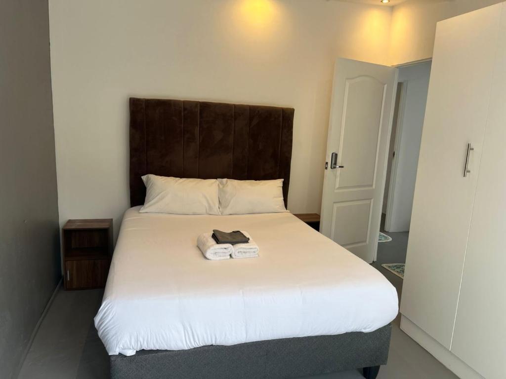 a bedroom with a large white bed with a wooden headboard at Blue Moon Charming 2 Bed Poolside Apartment in Bellville