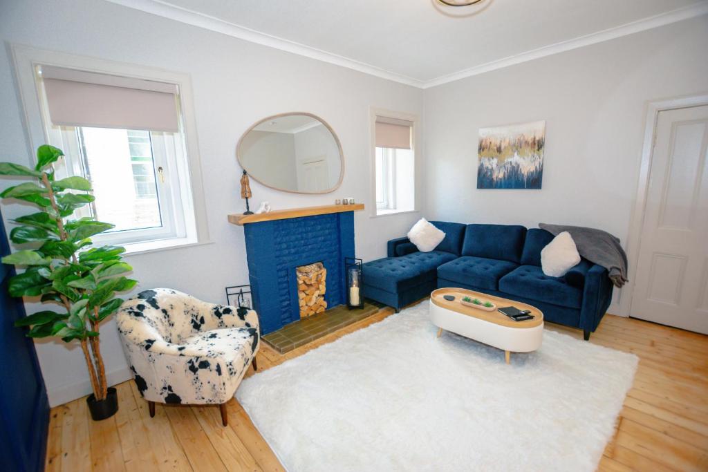 a living room with a blue couch and a fireplace at Limefield Residence in West Calder
