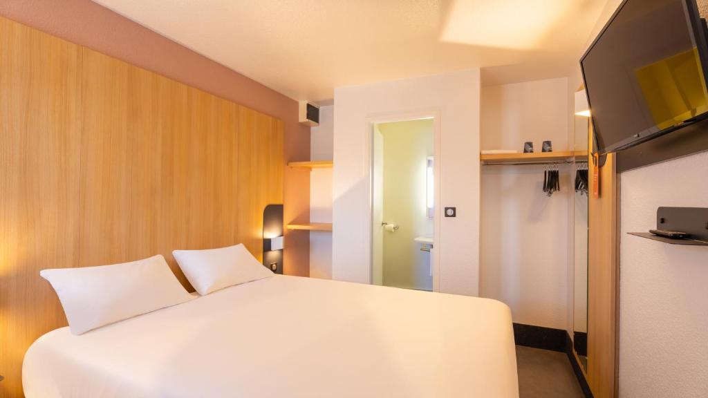 a bedroom with a white bed and a flat screen tv at Kyriad ECO - Lorient Lanester in Lanester