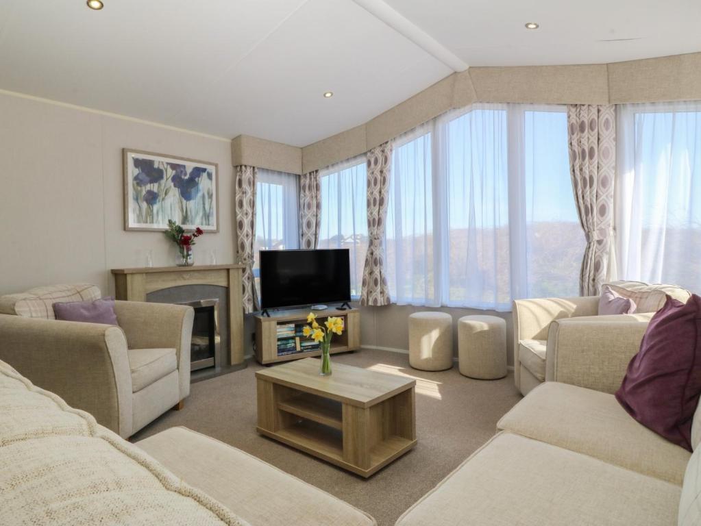a living room with couches and a flat screen tv at Pheasant Lodge in Holyhead