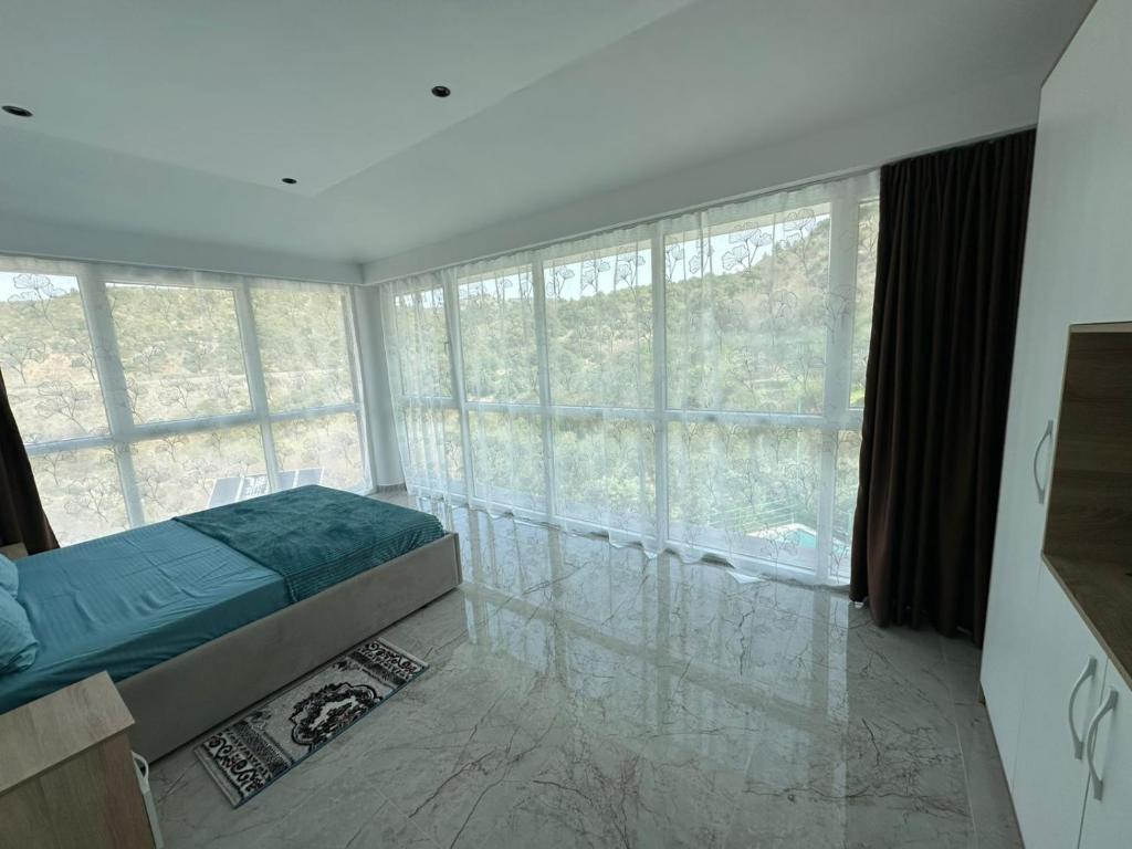 a bedroom with a bed and large windows at Qyteza guest house in Shkodër