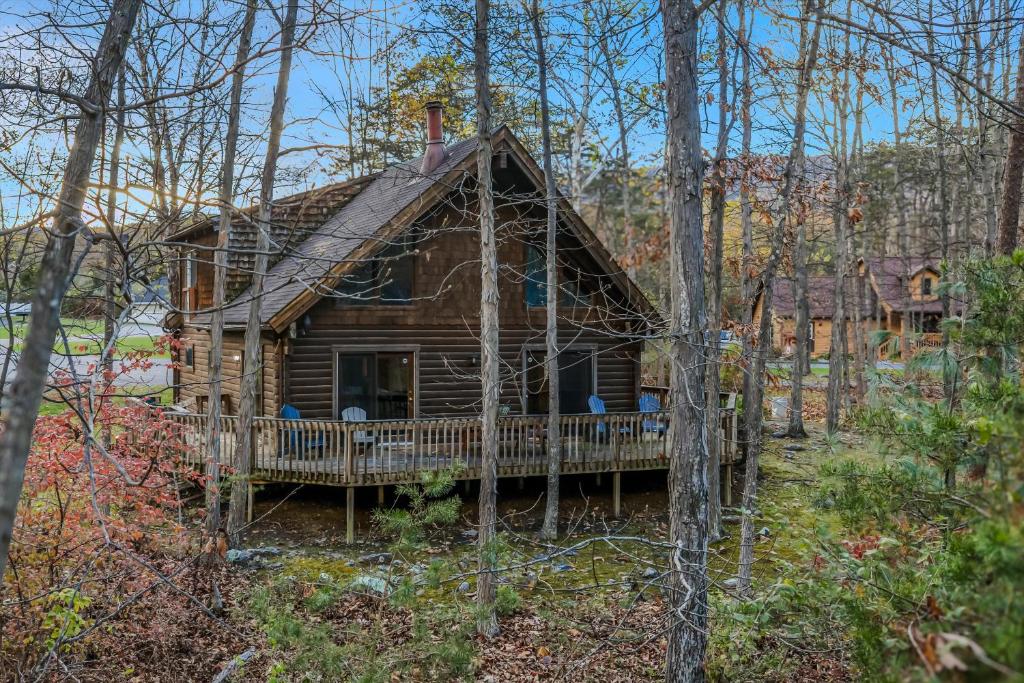 a log cabin with a porch in the woods at Lazy Bear Retreat - Wifi, Pet Friendly, Grill, Fire Pit, Fireplace, Deck, Golf, Hiking in Morton Grove