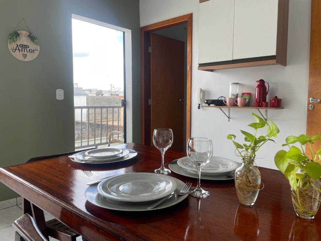 a wooden table with plates and wine glasses on it at Flat Centro 302 in Tangara da Serra
