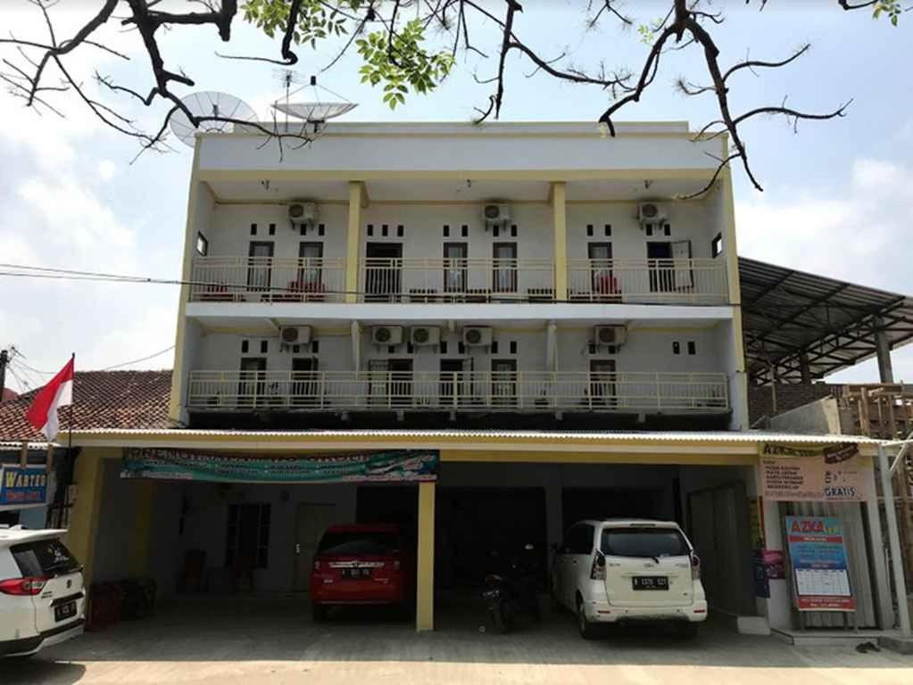 a white building with cars parked in front of it at Penginapan Dillah HO in Babagan