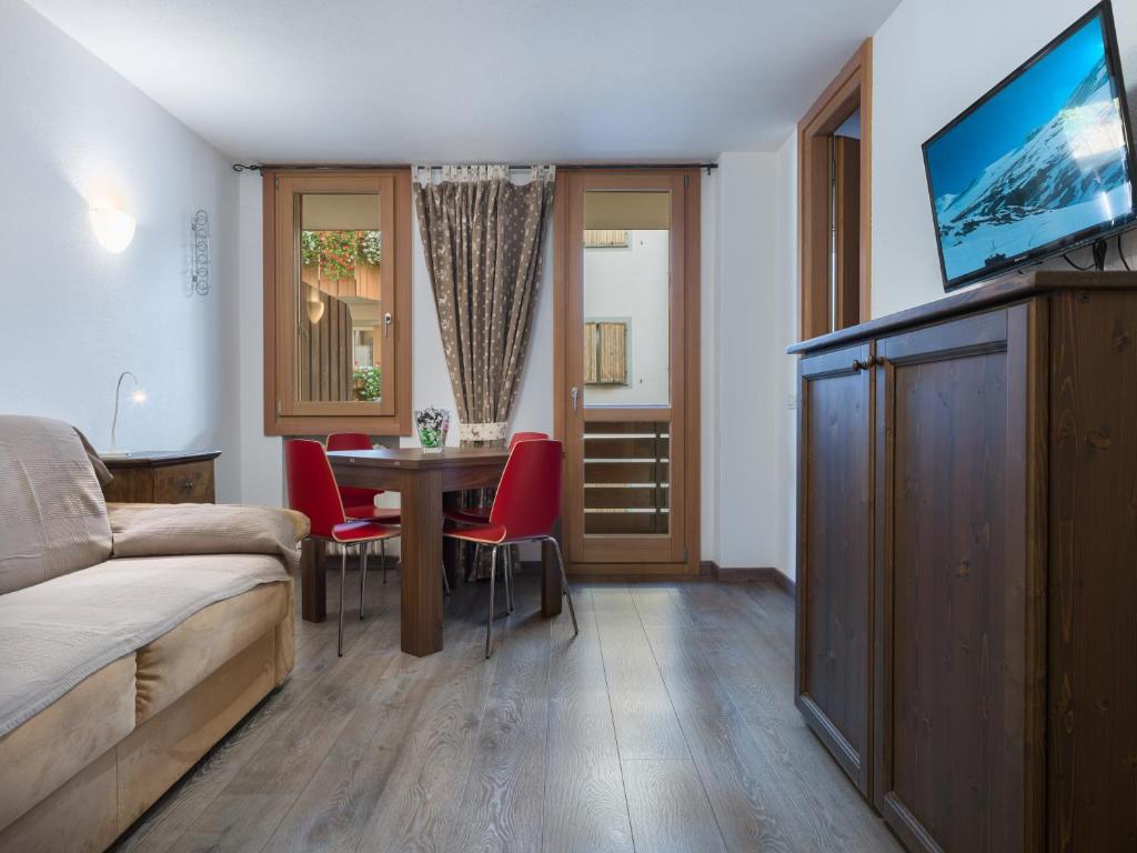 a living room with a bed and a table with red chairs at Casa Beba in Bormio