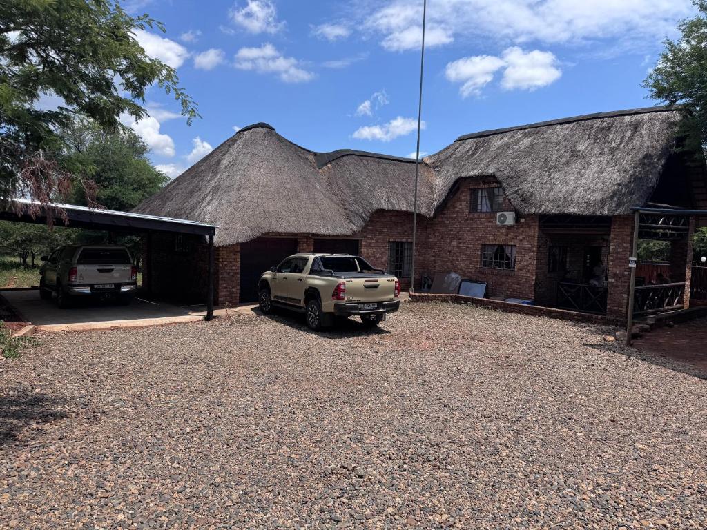 a car parked in front of a building with a thatched roof at Indlovu Inn in Marloth Park