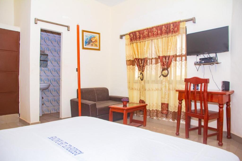 a bedroom with a bed and a desk and a couch at Hotel Résidence Les Racines in Pira