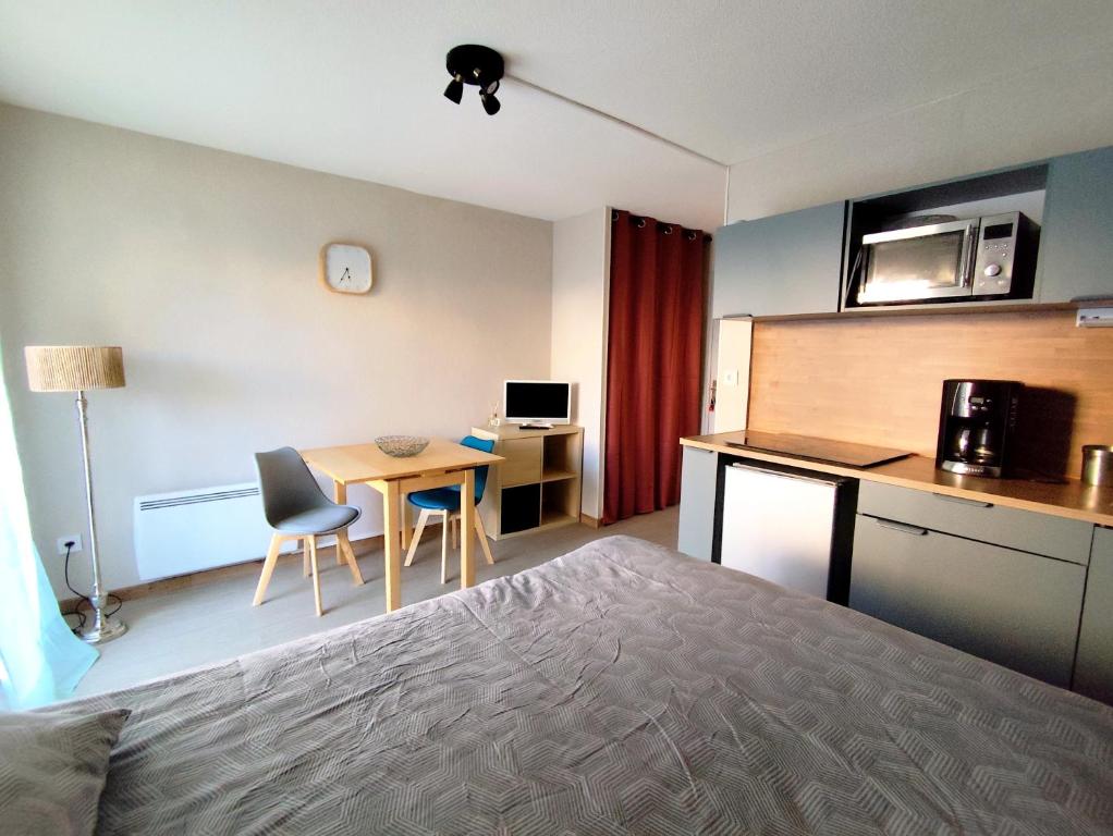 a room with a bed and a table and a kitchen at Studio Rénové - Le Verdale in Lamalou-les-Bains