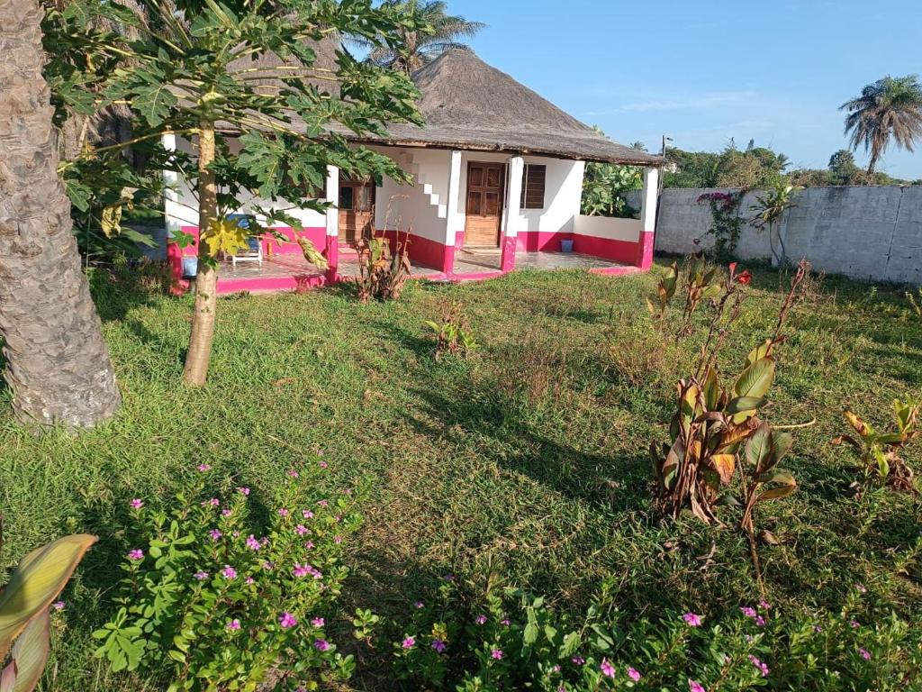 a pink and white house with a tree in a yard at Demba Dou Suites Gardens in Batukunku
