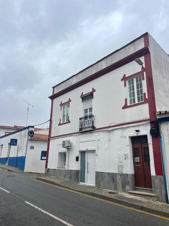 a white and red building on the side of a street at Casa Dona Joaquina in Reguengos de Monsaraz