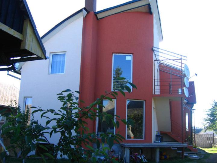 een rood-wit huis met een hond in het raam bij Pensiunea Claudia in Beliş