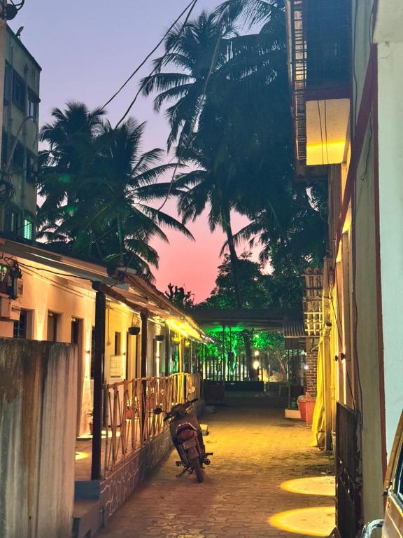a scooter parked on a street with a palm tree at Shree Savali Cottage in Revadanda