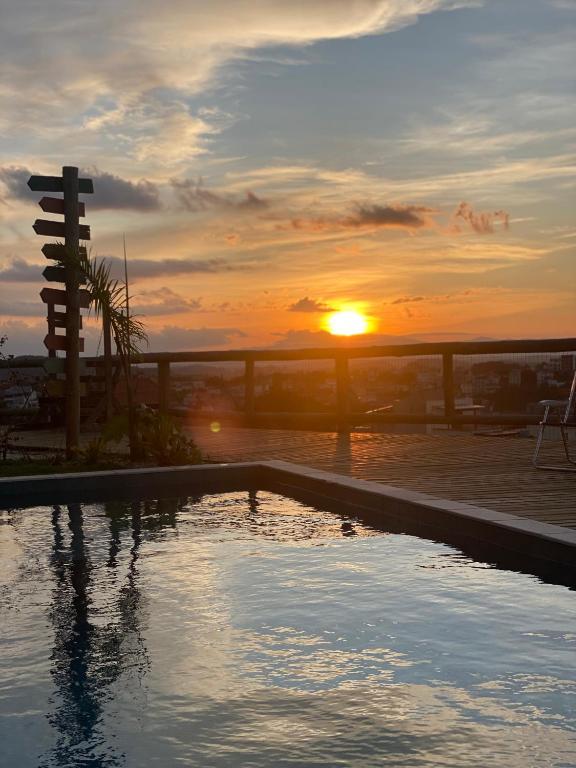 a swimming pool with the sunset in the background at Pousada Recanto Namastê - Mandalah in Cunha