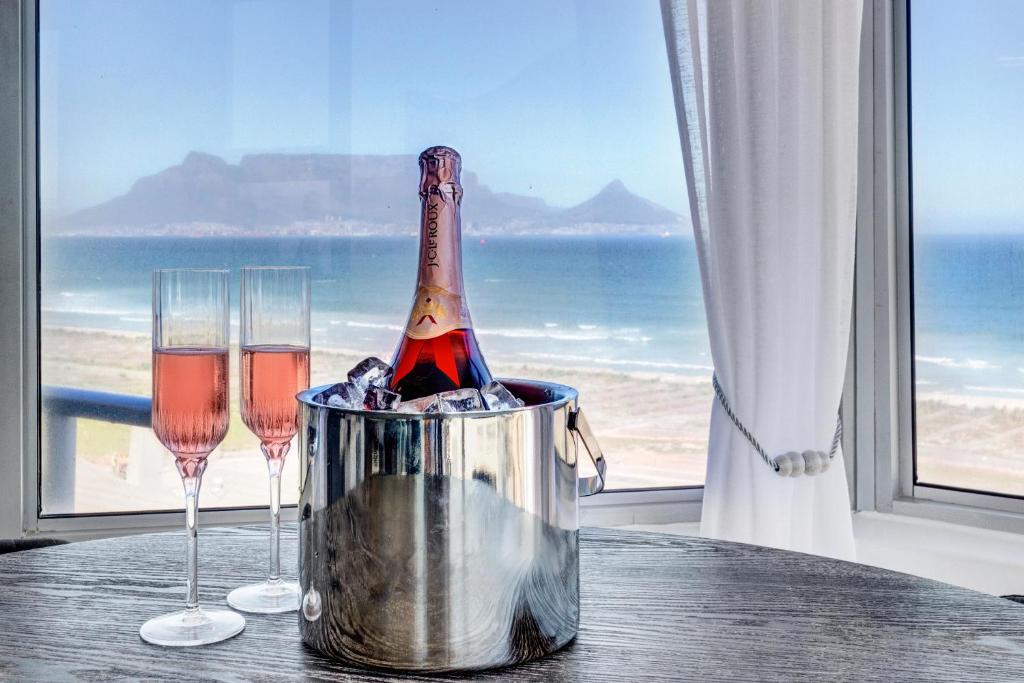 a bottle of champagne in a bucket on a table with two glasses at Mountain Tide in Cape Town