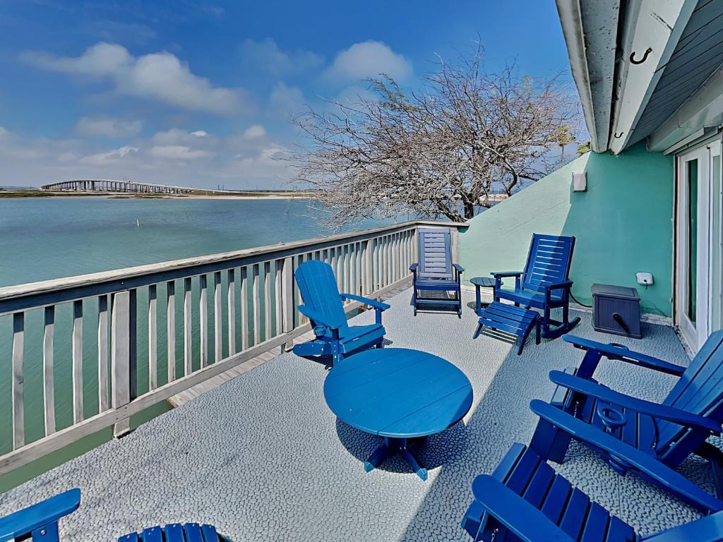 a group of chairs and tables on a balcony overlooking the water at Cozy Coastal Repose in Padre Island