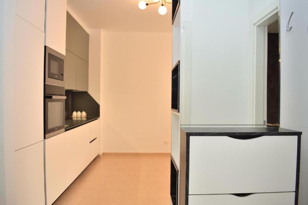 a kitchen with white cabinets and a refrigerator at Garden apartment in Vala Mar in Hamallë
