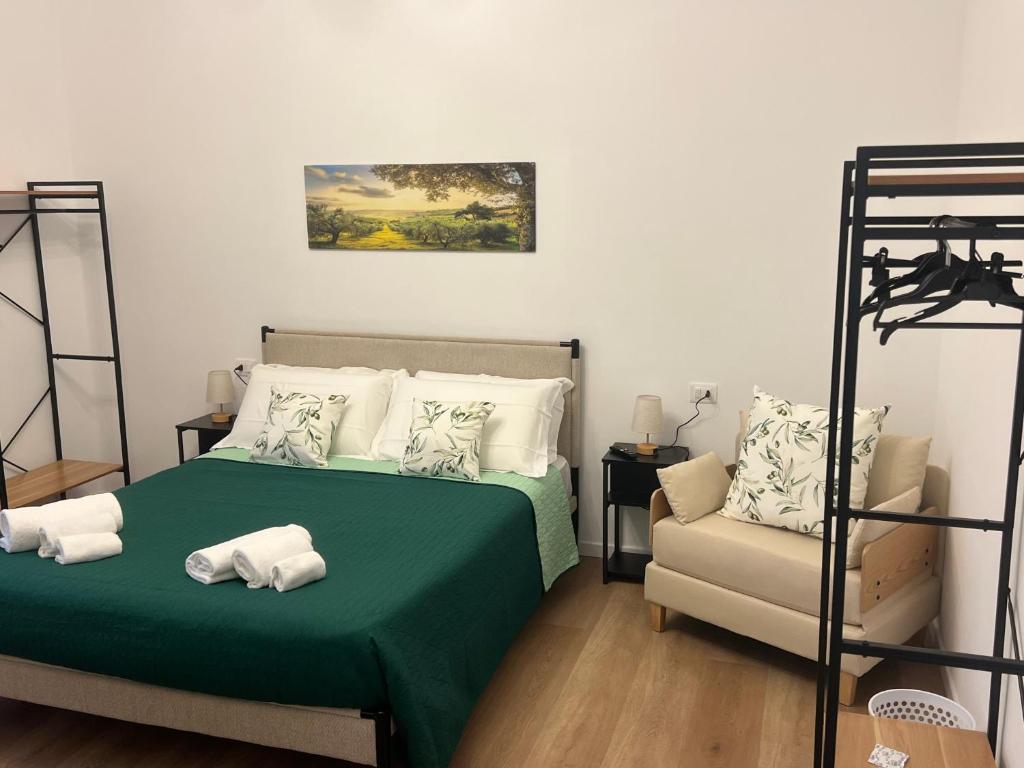 a bedroom with a green bed and a chair at Le Camere di Don Nicó in Tarquinia