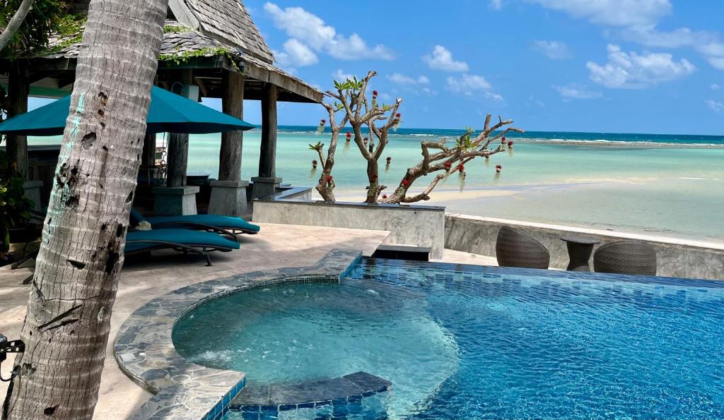 a swimming pool next to a beach with the ocean at Villa Sunrise - Golden Beachfront in Nathon Bay