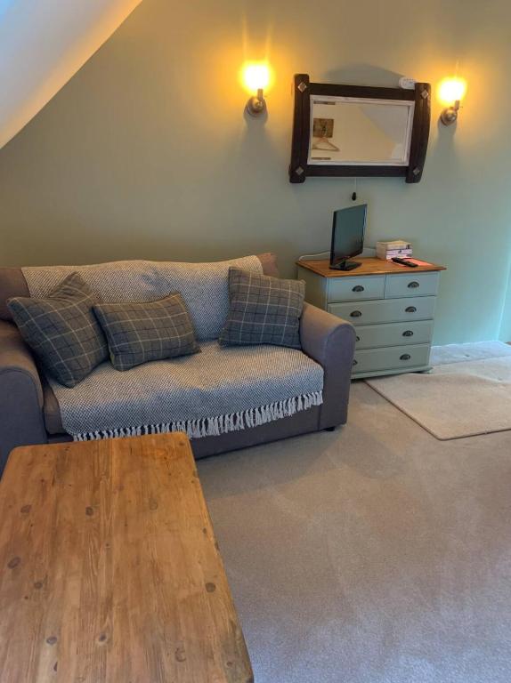 a living room with a couch and a dresser with a mirror at Corner Lodge in North Tawton