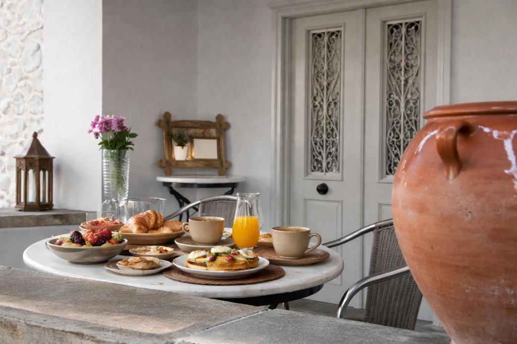 a table with plates of food and cups of orange juice at Lemon House in Hydra