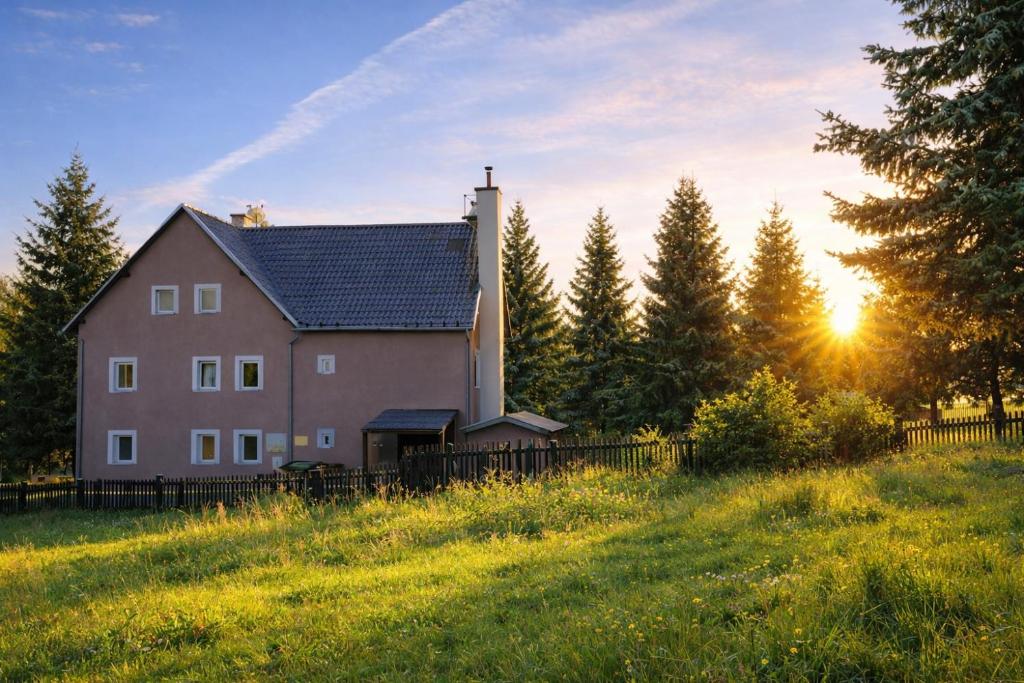 a house on a hill with the sun in the background at Forest House near Klínovec with 5 Independent Apartments in Kovářská