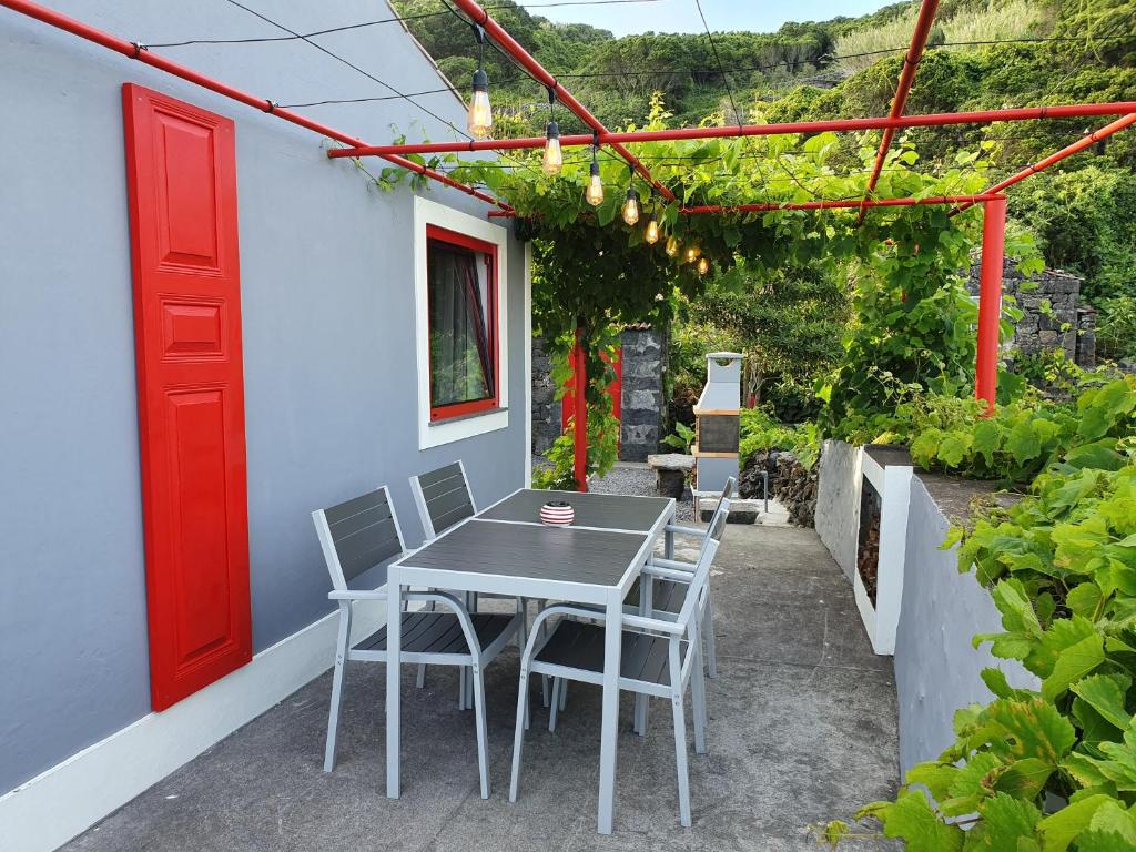 a table and chairs on a patio with a red door at Casinha de Nesquim in Calheta de Nesquim