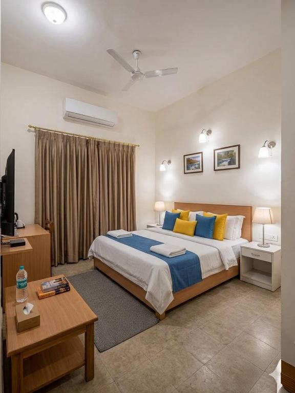 a bedroom with a large bed with blue and yellow pillows at Krishna Kunj Resort in Chhatikara