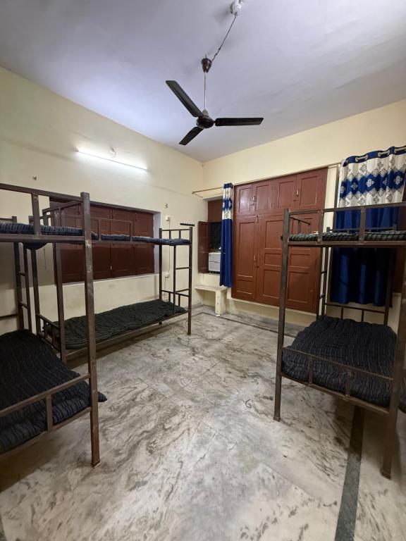 a room with three bunk beds and a ceiling fan at Nook Coliving Male Only in Lucknow