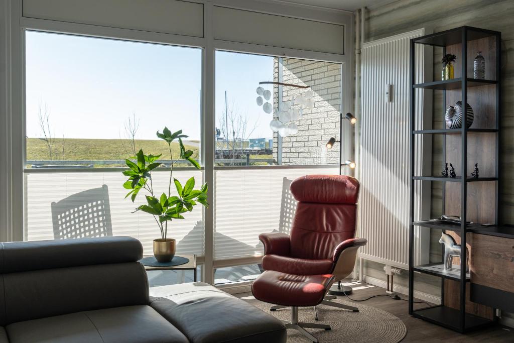 a living room with a chair and a large window at Apartment Deichblick in Büsum