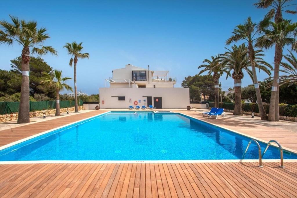 a swimming pool in front of a villa with palm trees at Stunning duplex with two terraces in Cala Blanca in Son Carrio