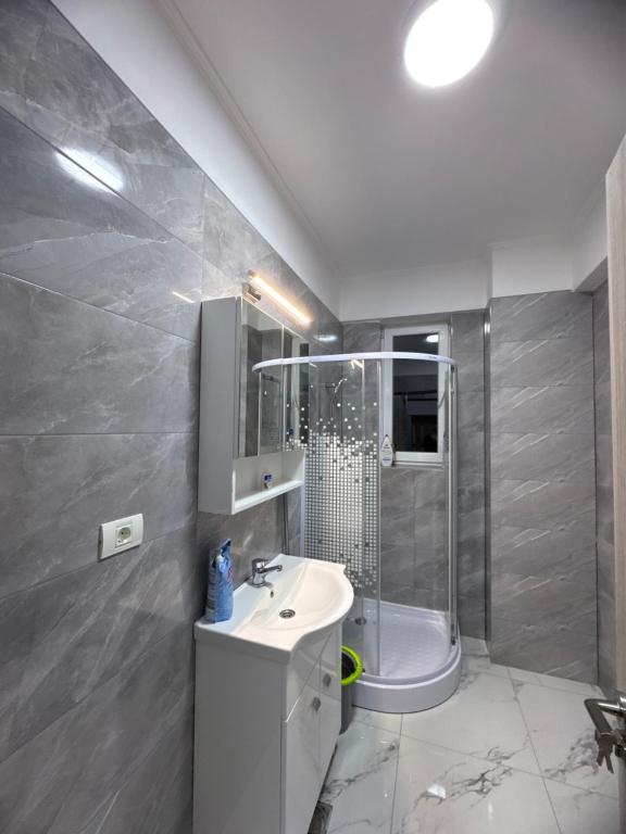 a bathroom with a white sink and a shower at Garsonieră in Tulcea