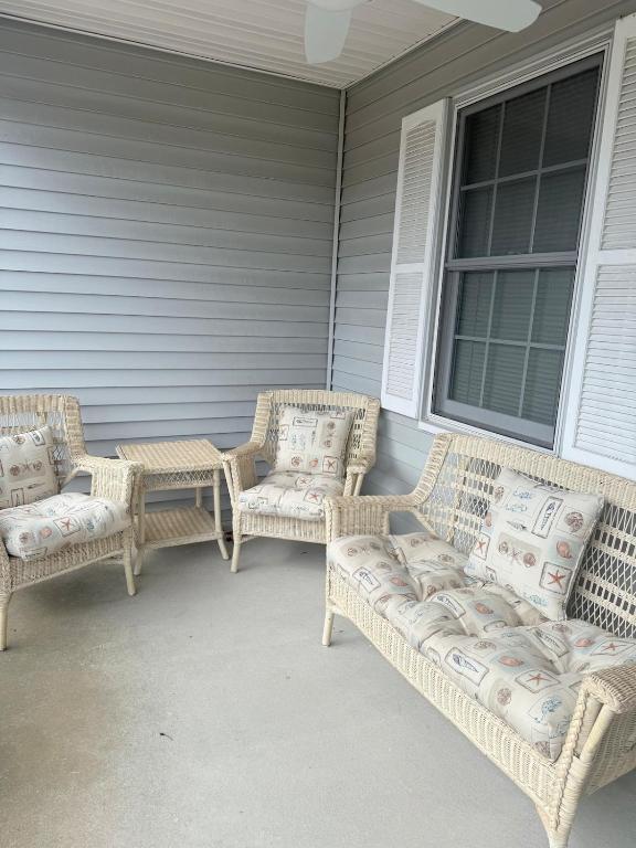 three wicker chairs and a table on a porch at Vermont By The Sea in Cape May