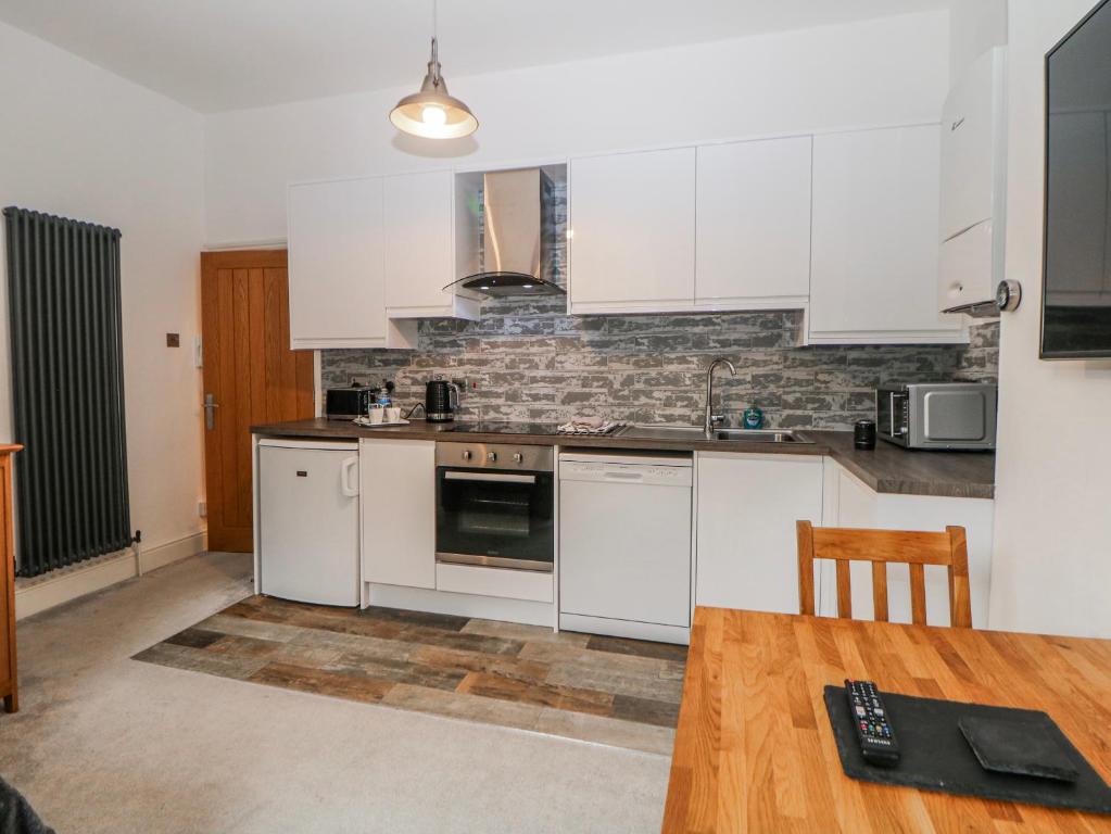 a kitchen with white cabinets and a wooden table at Masson in Matlock